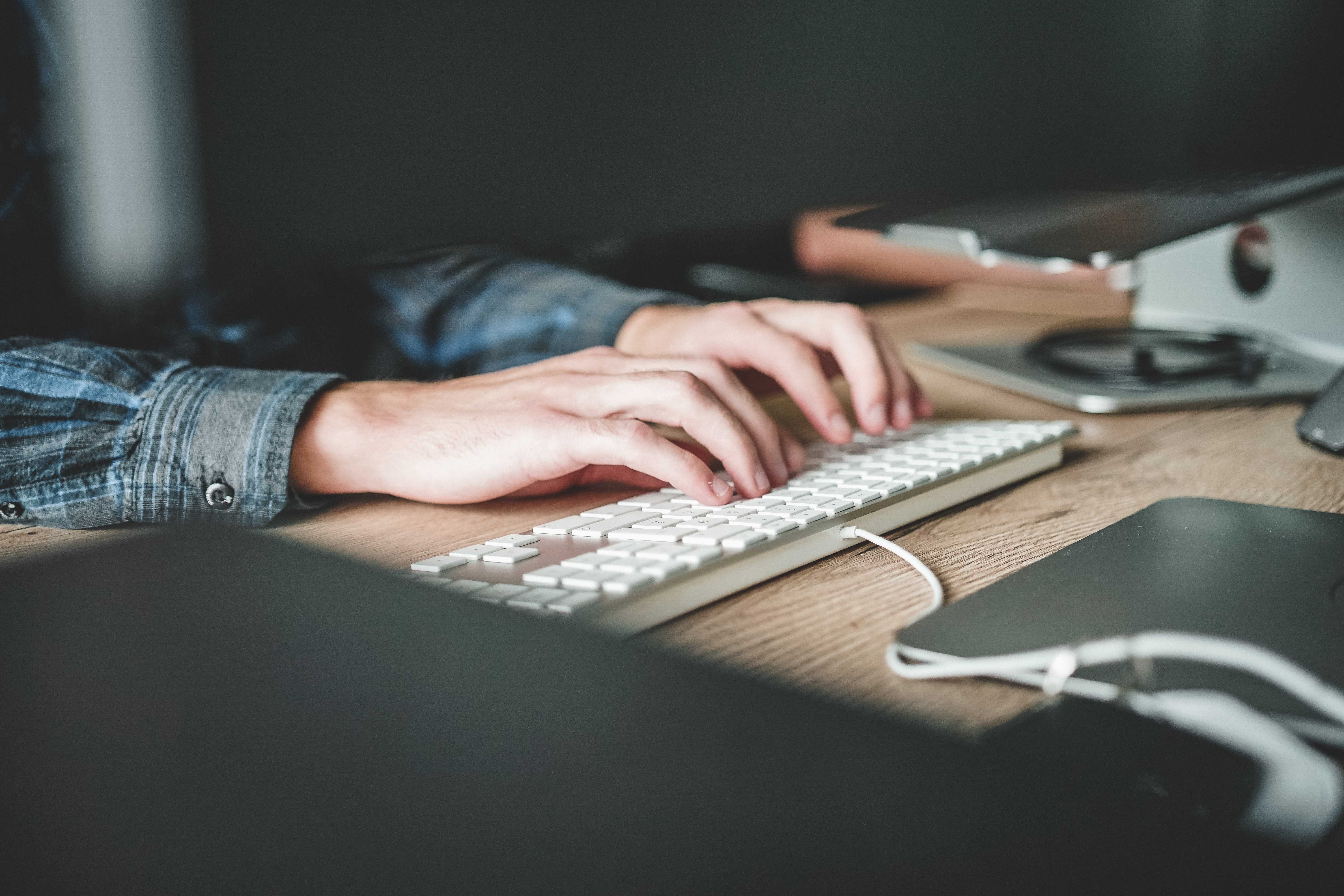 Detail of a workplace. Hands typing on a keyboard.
